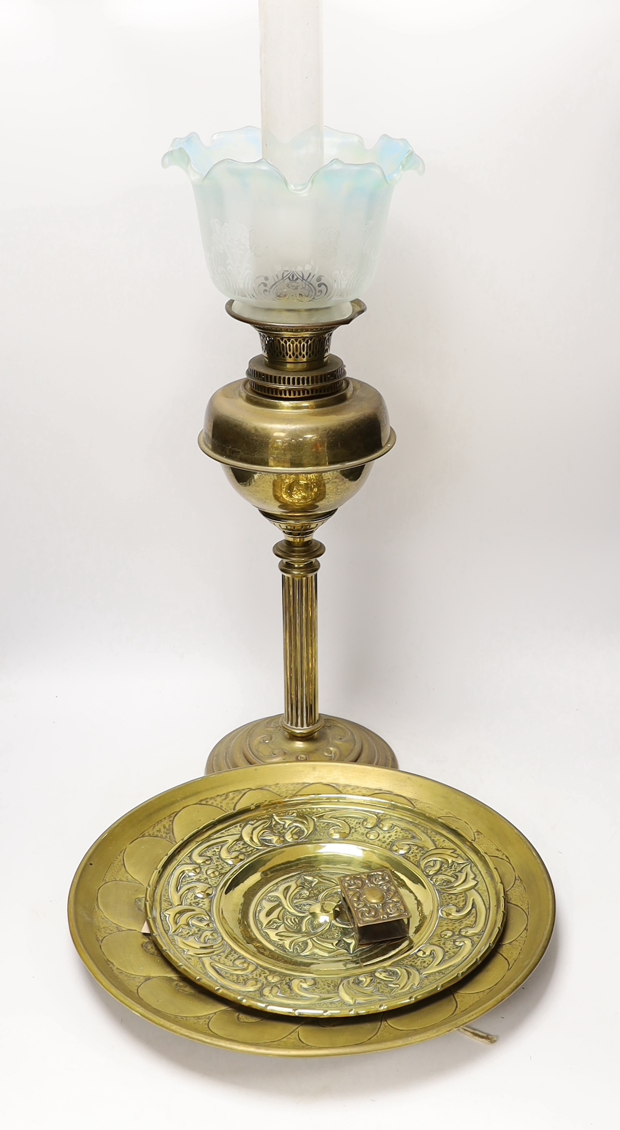 A Victorian brass oil lamp with glass shade, two brass chargers and a match box cover, oil lamp 72 cm high including funnel